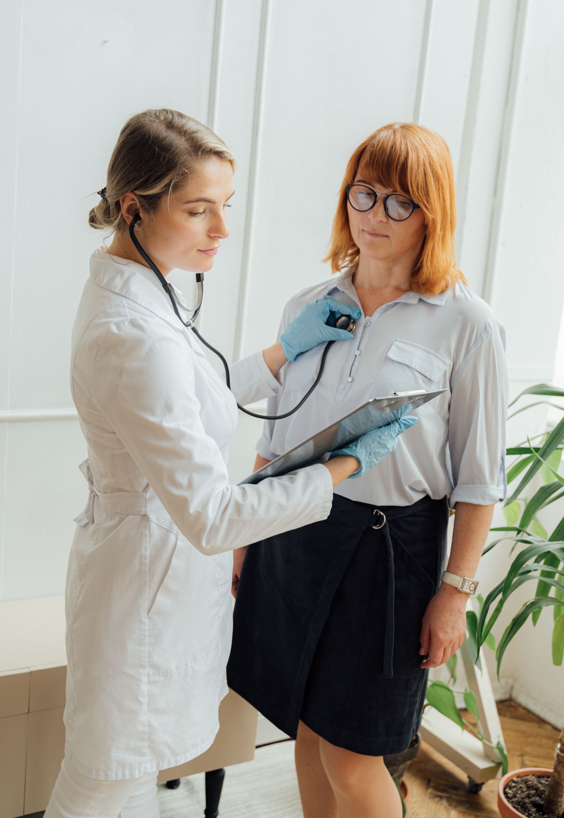 A clinician listening to a patient's heart with a stethoscope